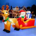 Inflatable Santa and snowman in a red sleigh behind a brown reindeer in a snowy yard