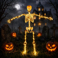 Poseable skeleton lit with warm LED lights and red eyes standing in a graveyard scene with jack-o'-lanterns