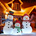 Three lighted snowman figures in hats and scarves glowing in front of a house