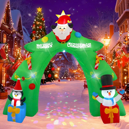 Green inflatable Christmas archway with Santa on top and a penguin and snowman at the base on a snowy street at night